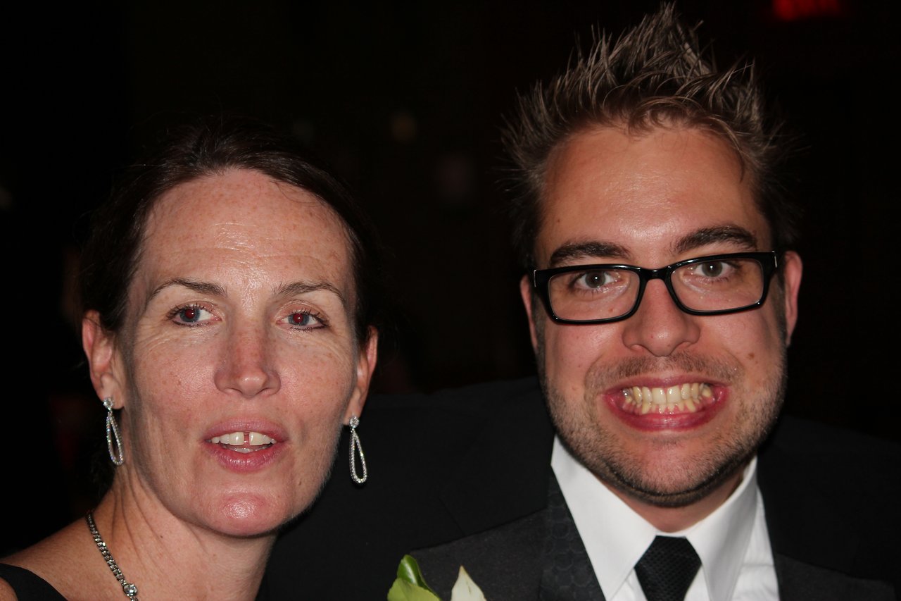 Two people posing at an award banquet, one smiling widely and the other looking slightly off-camera.
