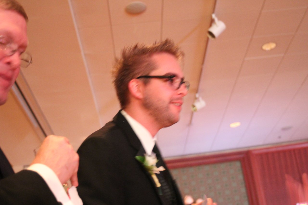 A man in a suit with a boutonniere walks through the banquet hall during the award event.
