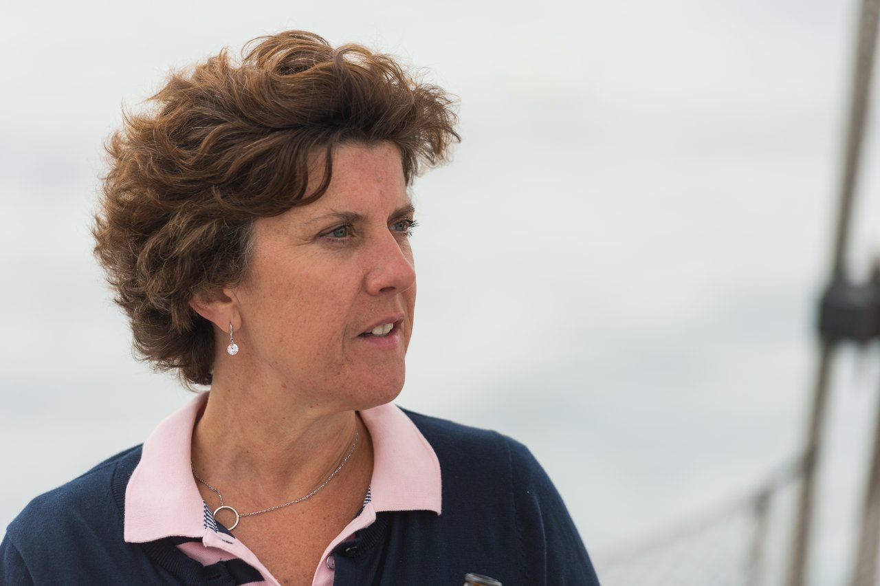 A woman on a boat looks to the side with a focused expression.