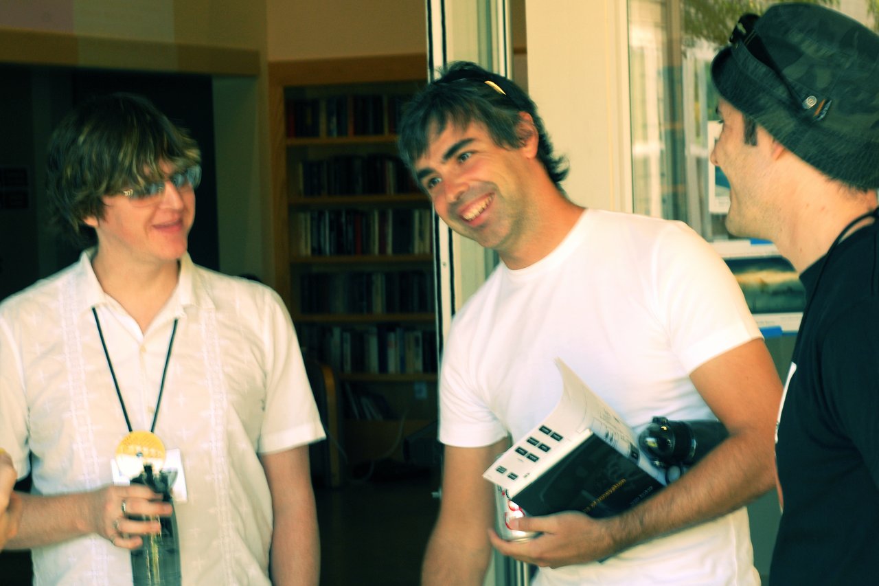 Three men stand together, smiling and talking.