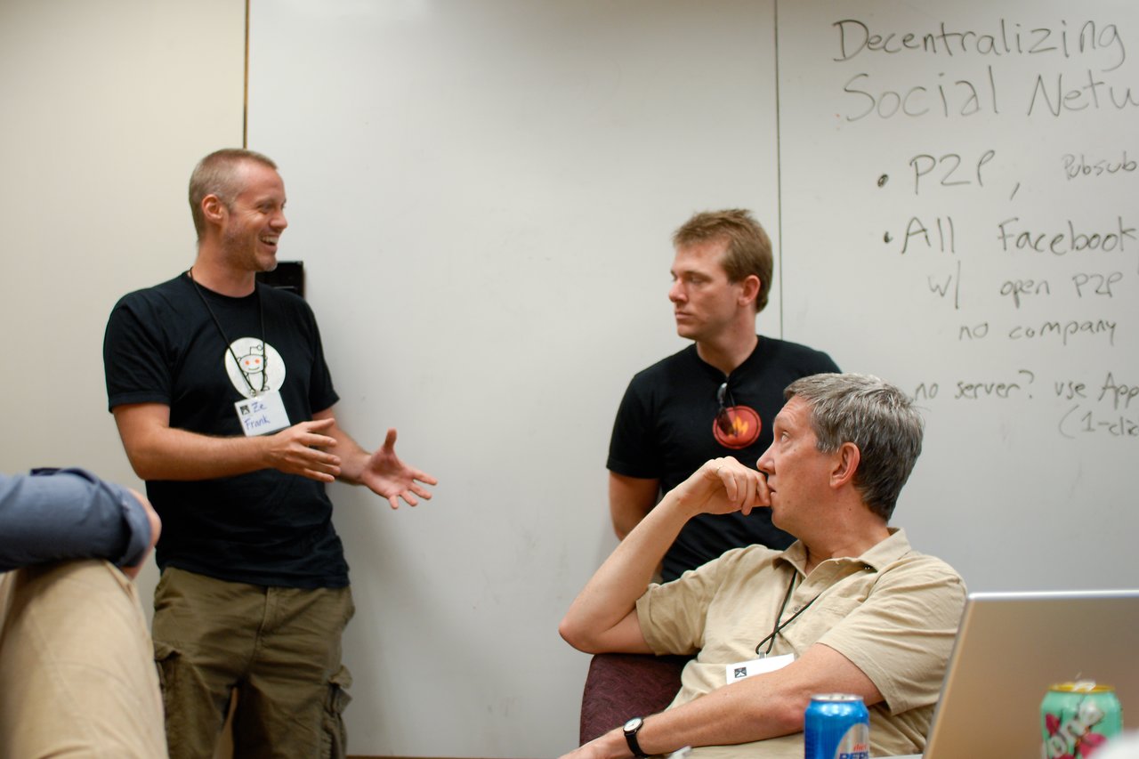 Three people in discussion, with one gesturing while speaking.