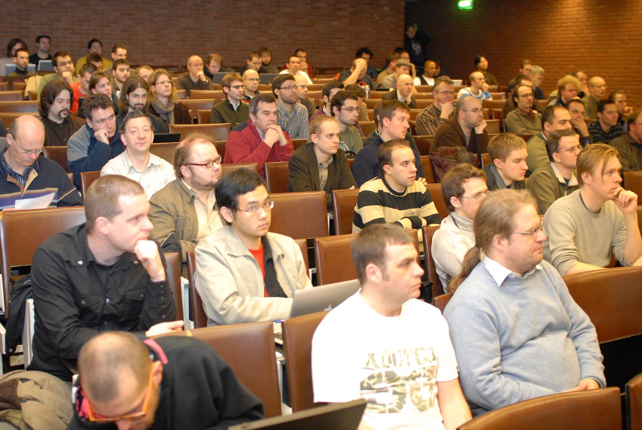A group of people attentively listening in the Drupal developer room at FOSDEM 2008.