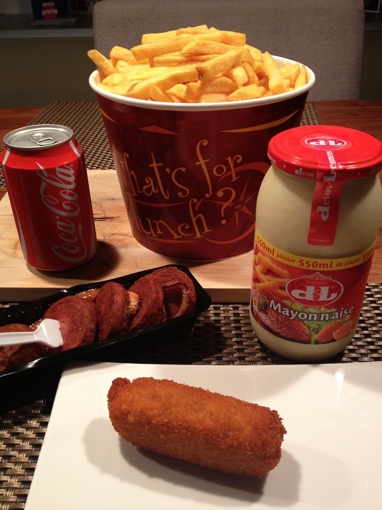 A large bucket of fries, a croquette on a plate, a can of Coca-Cola, and mayonnaise.
