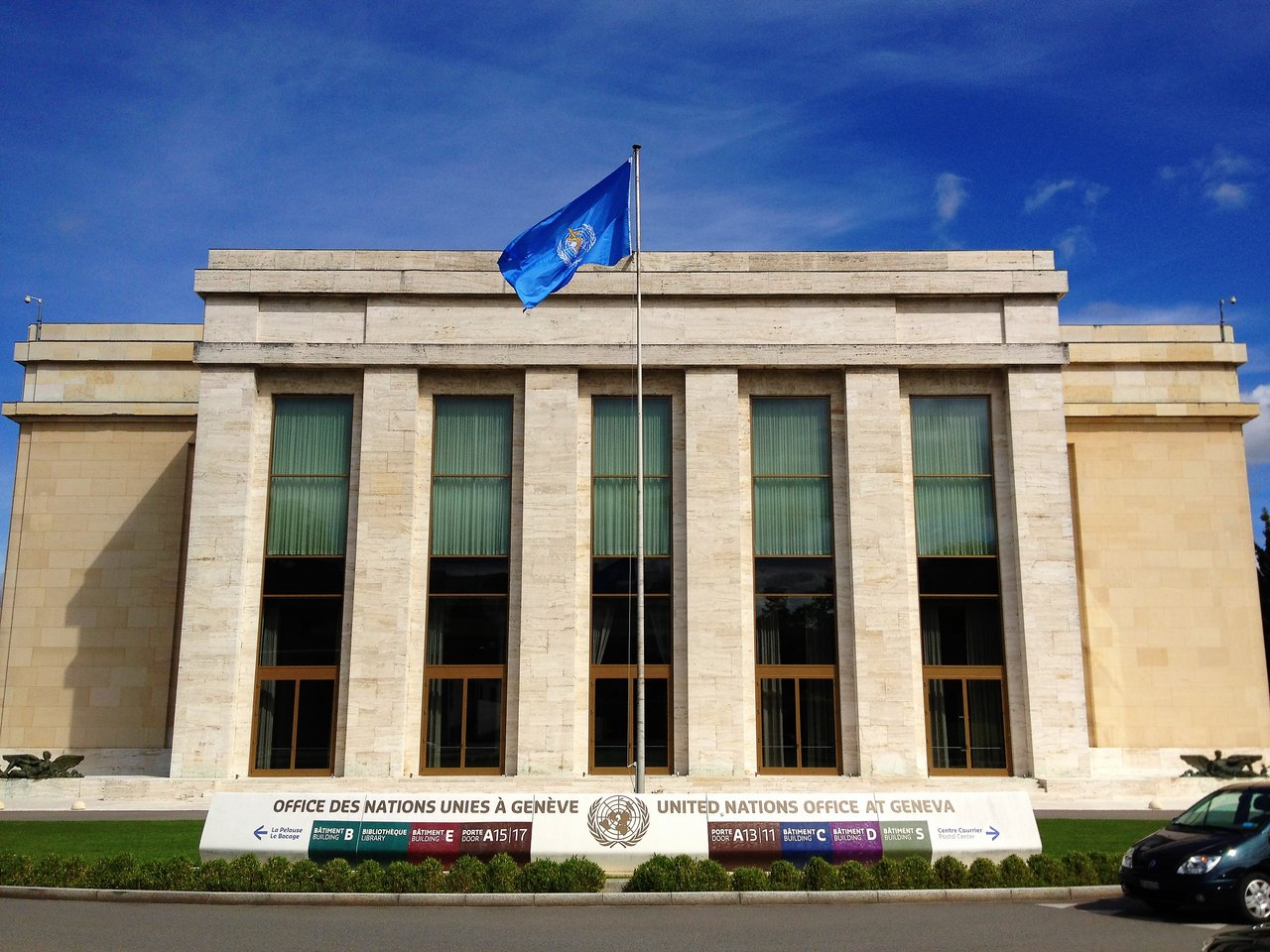 The United Nations Office at Geneva building with a UN flag flying on a pole in front.