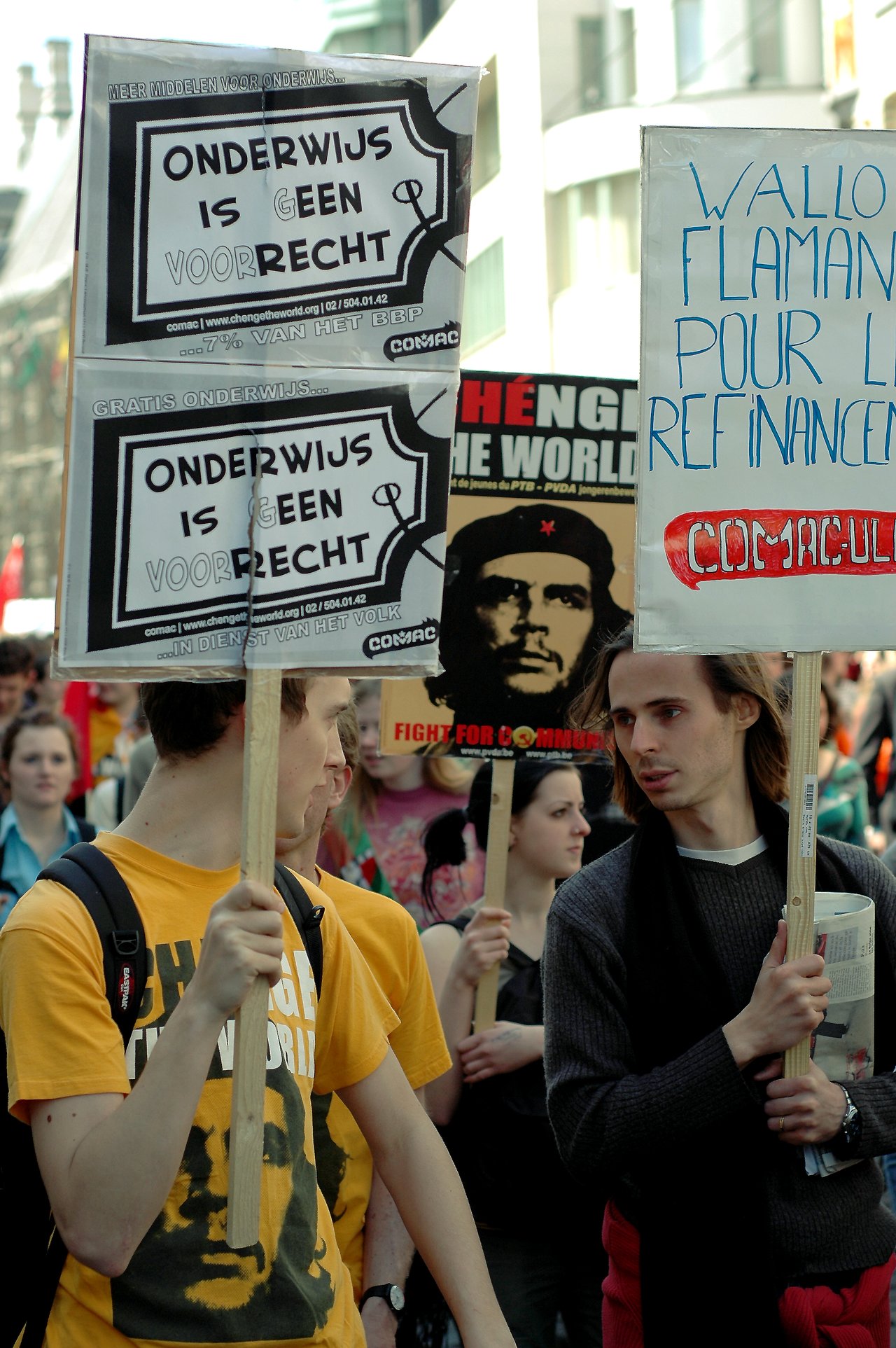Protesters hold signs demanding accessible education and funding while discussing their message during a demonstration.