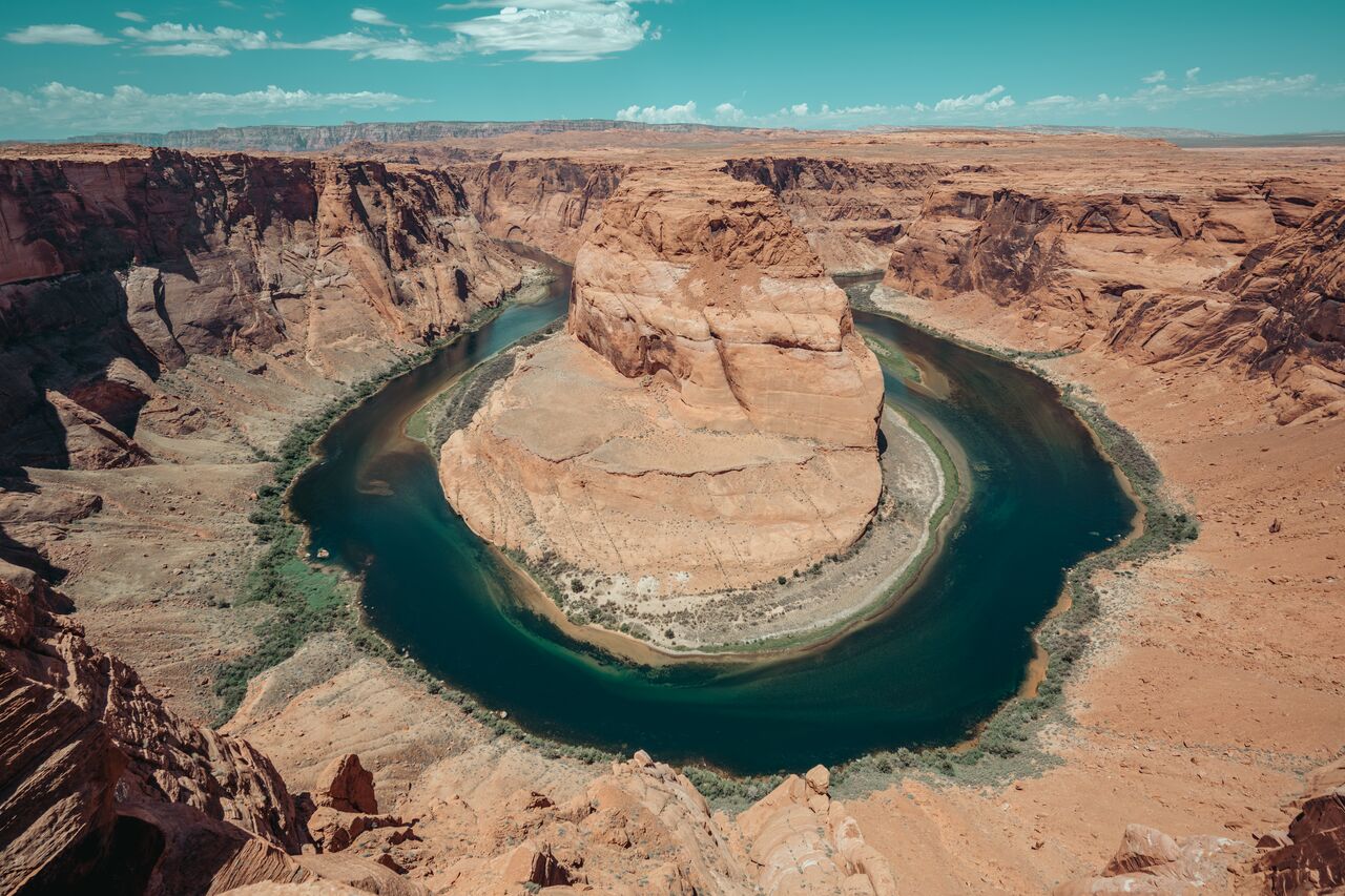 A view of a wide, U-shaped bend in the Colorado River surrounded by steep red rock cliffs.