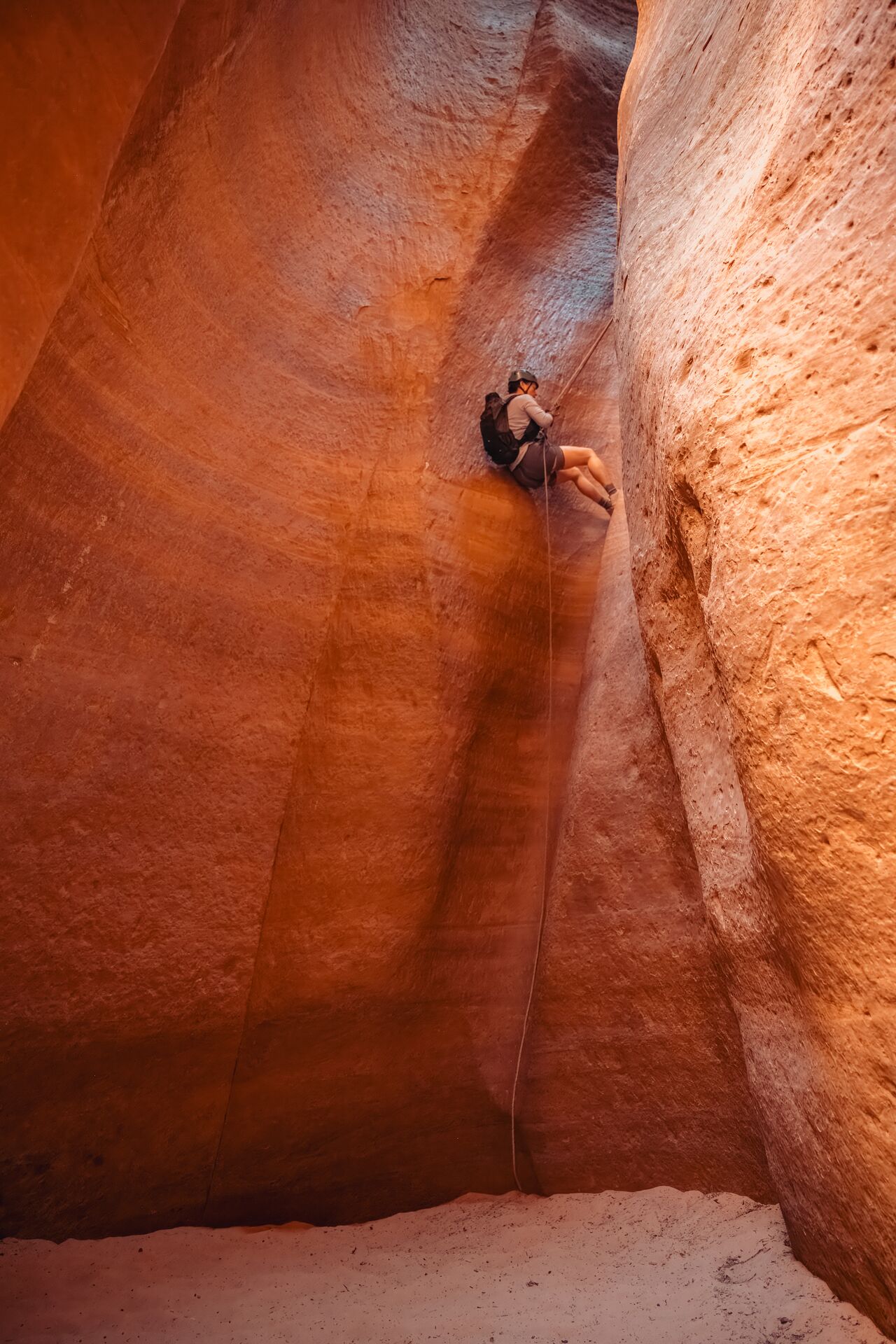 Person rappelling down a tall sandstone wall in Zion National Park.