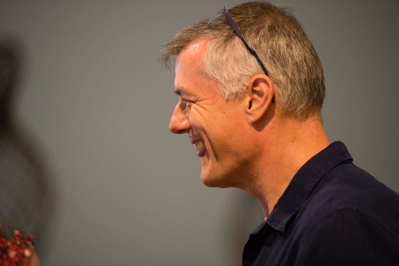 A man in a dark shirt smiles while talking at the Acquia awards dinner in Grand Cayman.