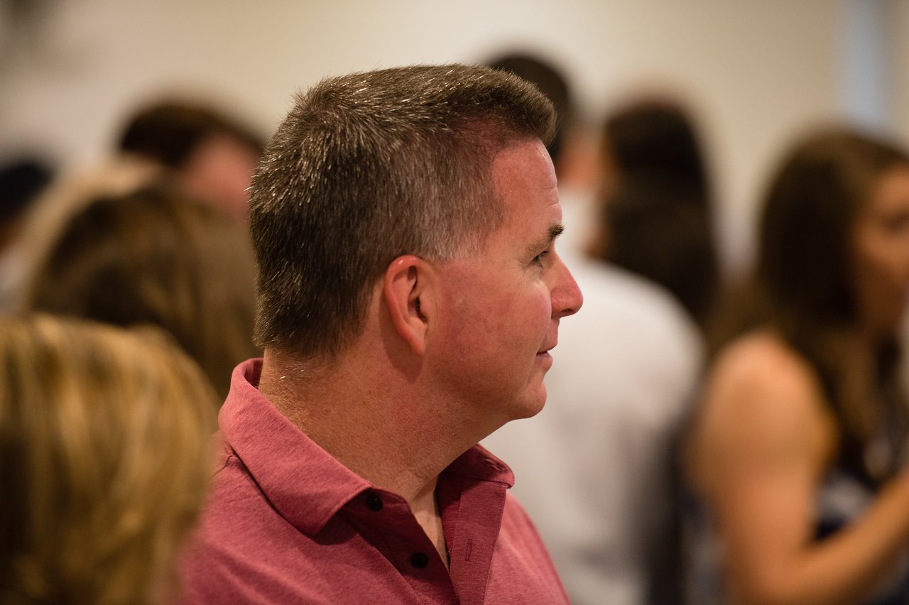 A man in a red shirt listens attentively during the Acquia awards dinner at the President's Club trip.