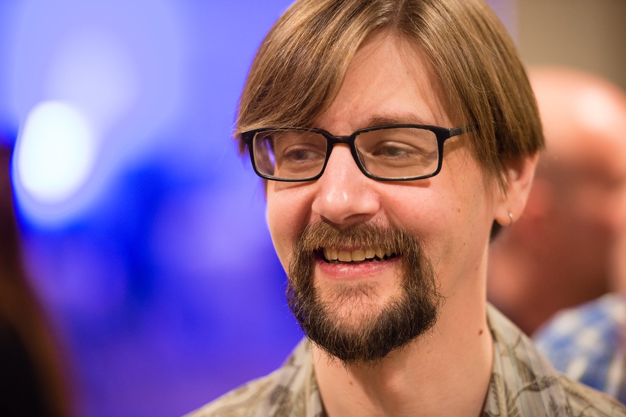 A man wearing glasses smiles during the Acquia President's Club awards dinner in Grand Cayman.