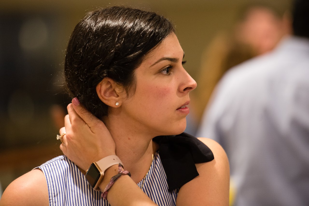 A woman at the awards dinner looks to the side while adjusting her hair, surrounded by other attendees.