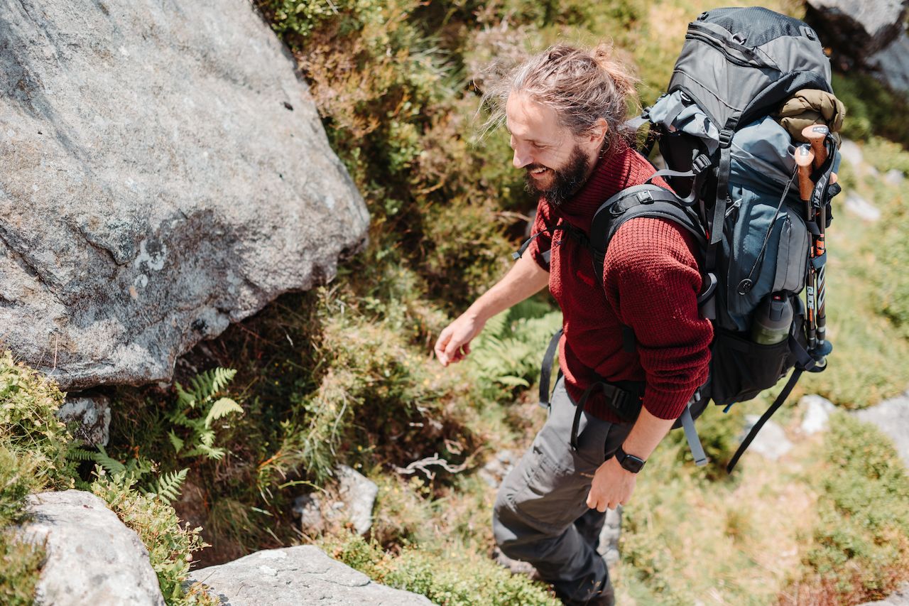 Klaas hiking up some rocks with a big backpack on
