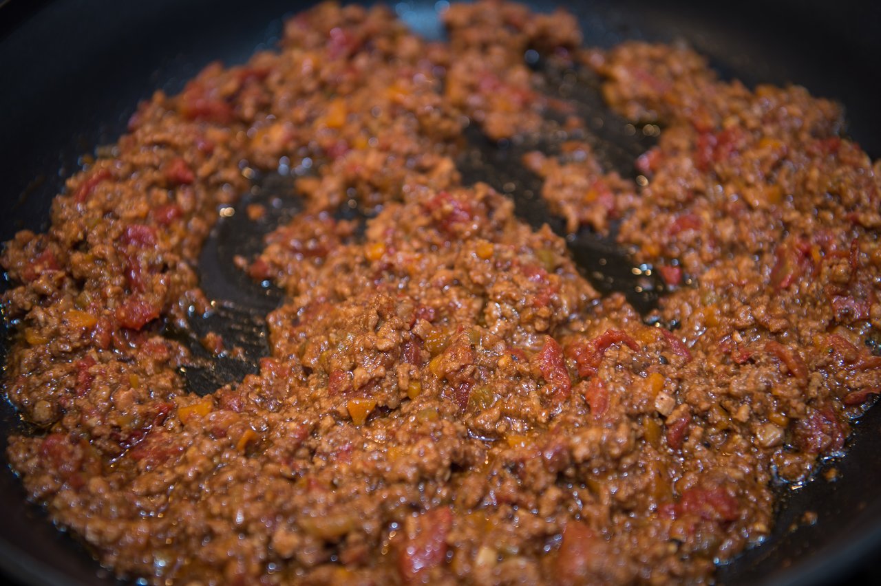 Ground meat and tomato sauce cooking in a pan, likely for a pasta dish.