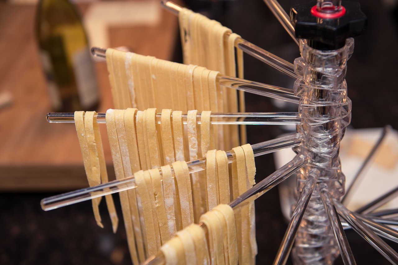 Freshly made pasta strips hanging on a drying rack.