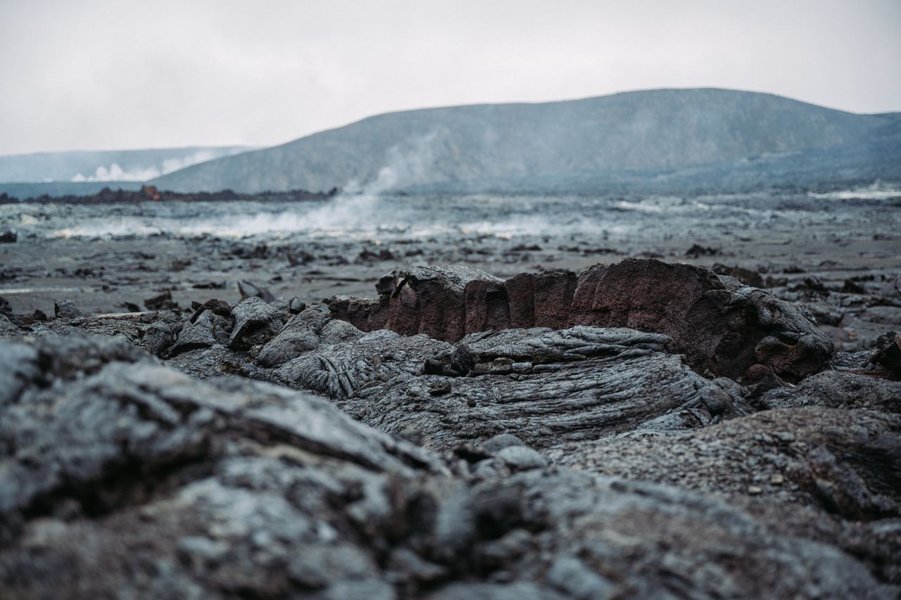 Close-up of hardened lava with steam rising in the distance at Gerlingadalur volcano, Iceland.
