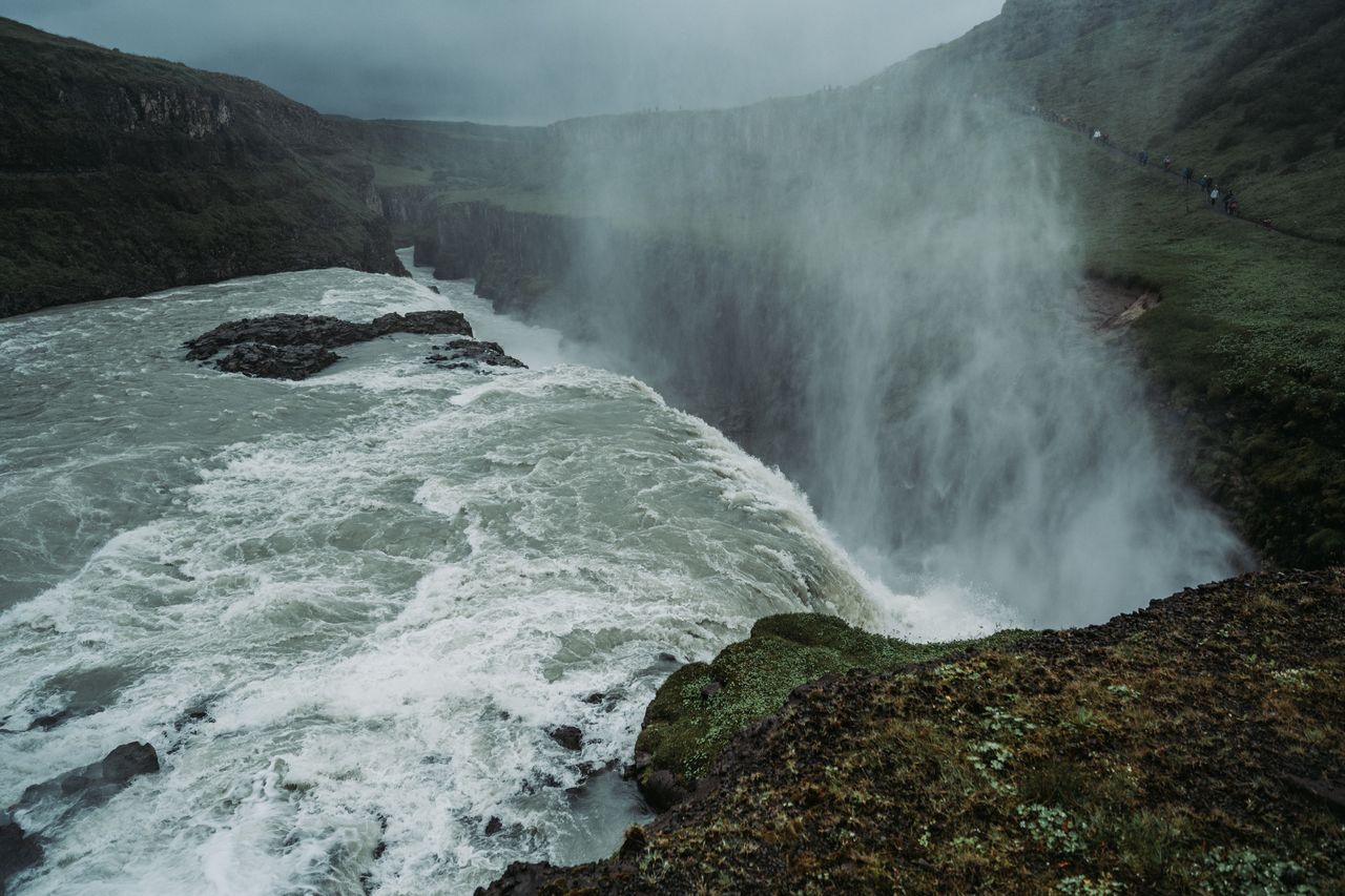 Powerful water flows over the edge of Gullfoss Falls in Iceland, creating mist as it crashes into the canyon below.