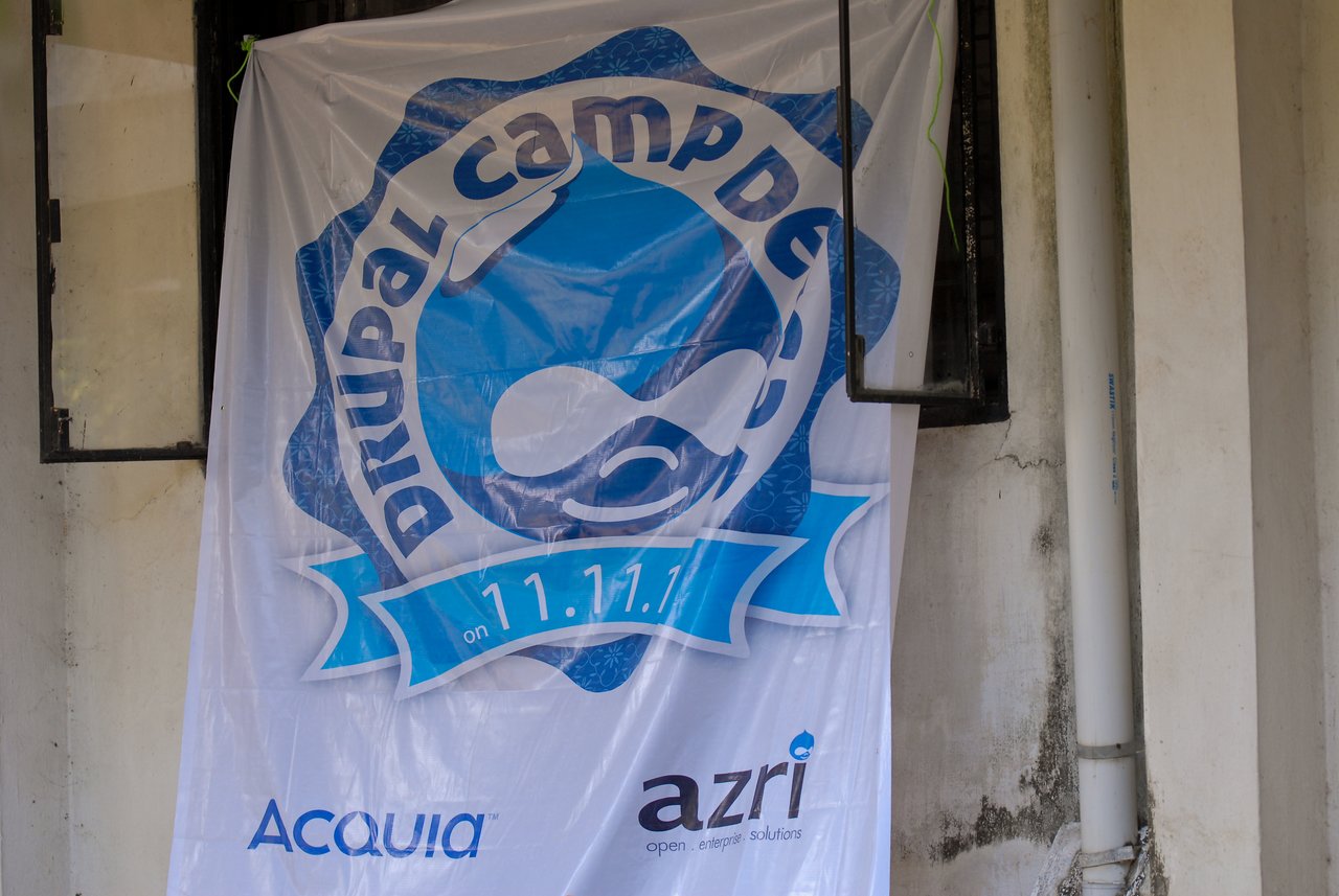 A large banner for DrupalCamp Deccan 2011 hangs outside, featuring the event logo and sponsor names.