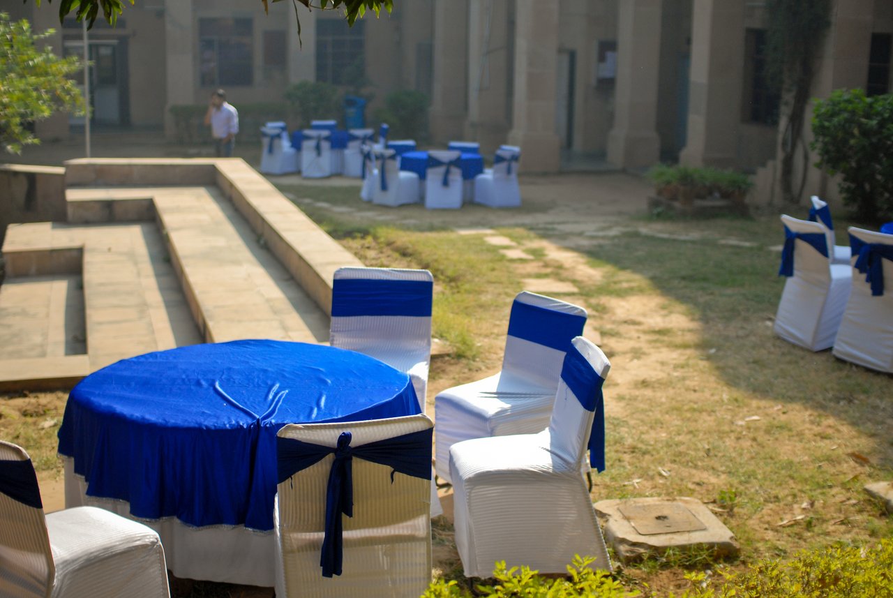 Outdoor seating area with white chairs and blue tablecloths, set up for a DrupalCamp Delhi code sprint.