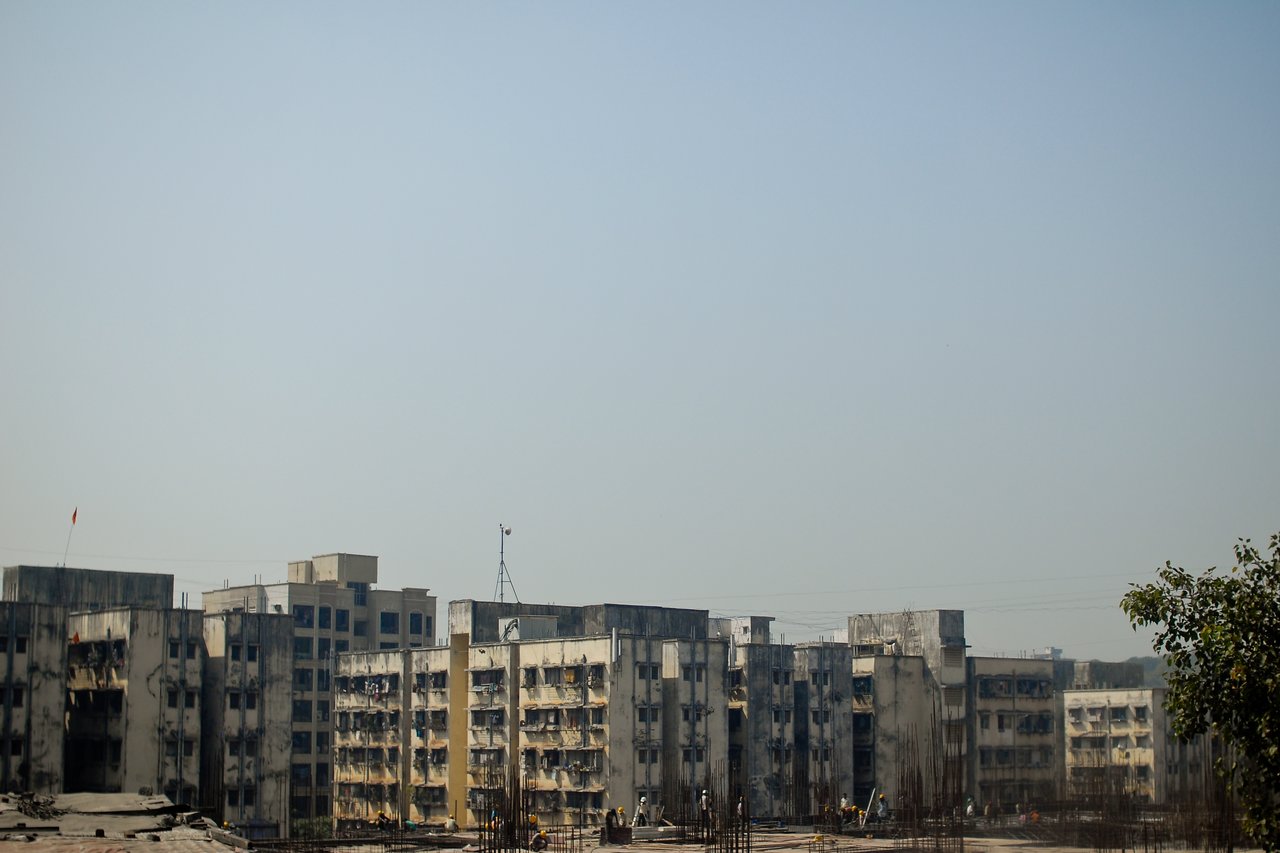 Old apartment buildings in Mumbai with visible wear, surrounded by construction work in the foreground.