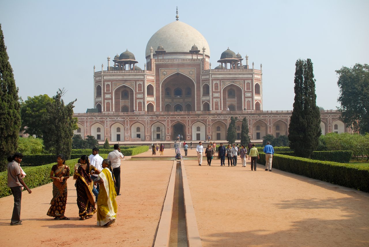 Humayun's Tomb in New Delhi with visitors walking along the pathway in the garden.