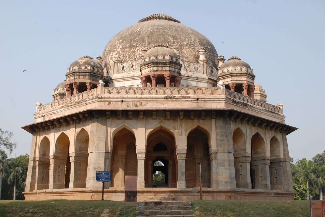 A historic stone tomb with a large dome and arched openings in Lodhi Gardens, New Delhi.