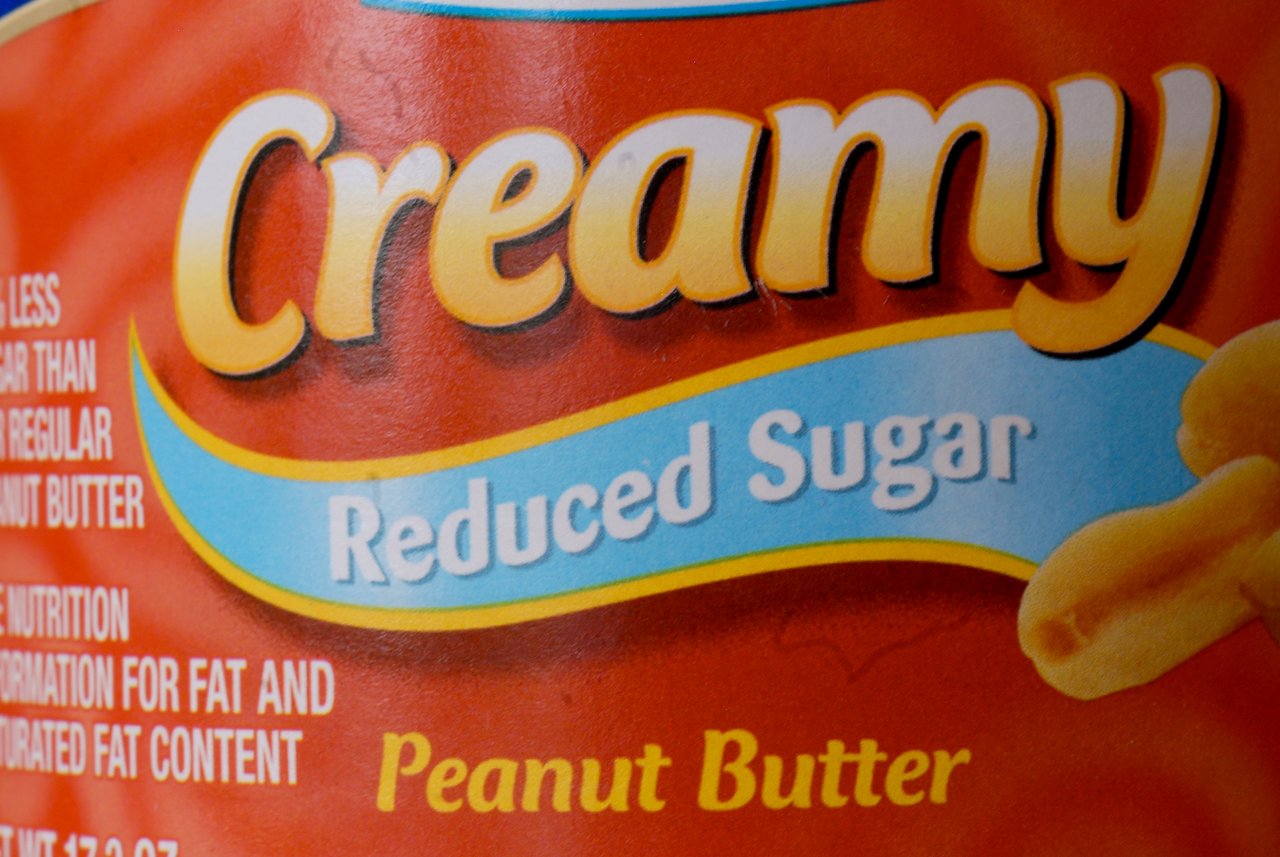 Close-up of a peanut butter jar label reading "Creamy Reduced Sugar Peanut Butter" with an image of peanuts.