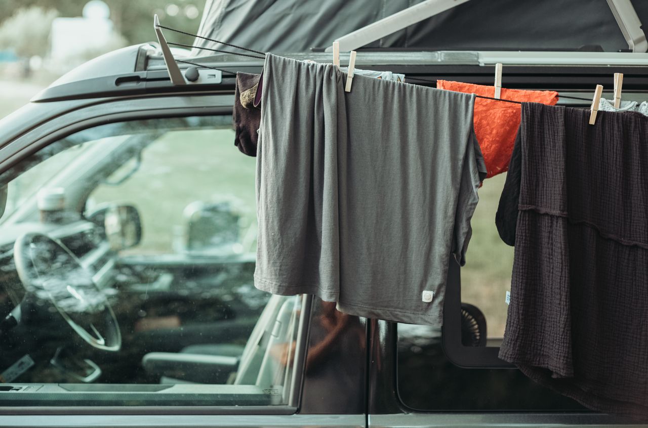 Clothes hanging on a line attached to a Volkswagen camper van, drying in the open air.