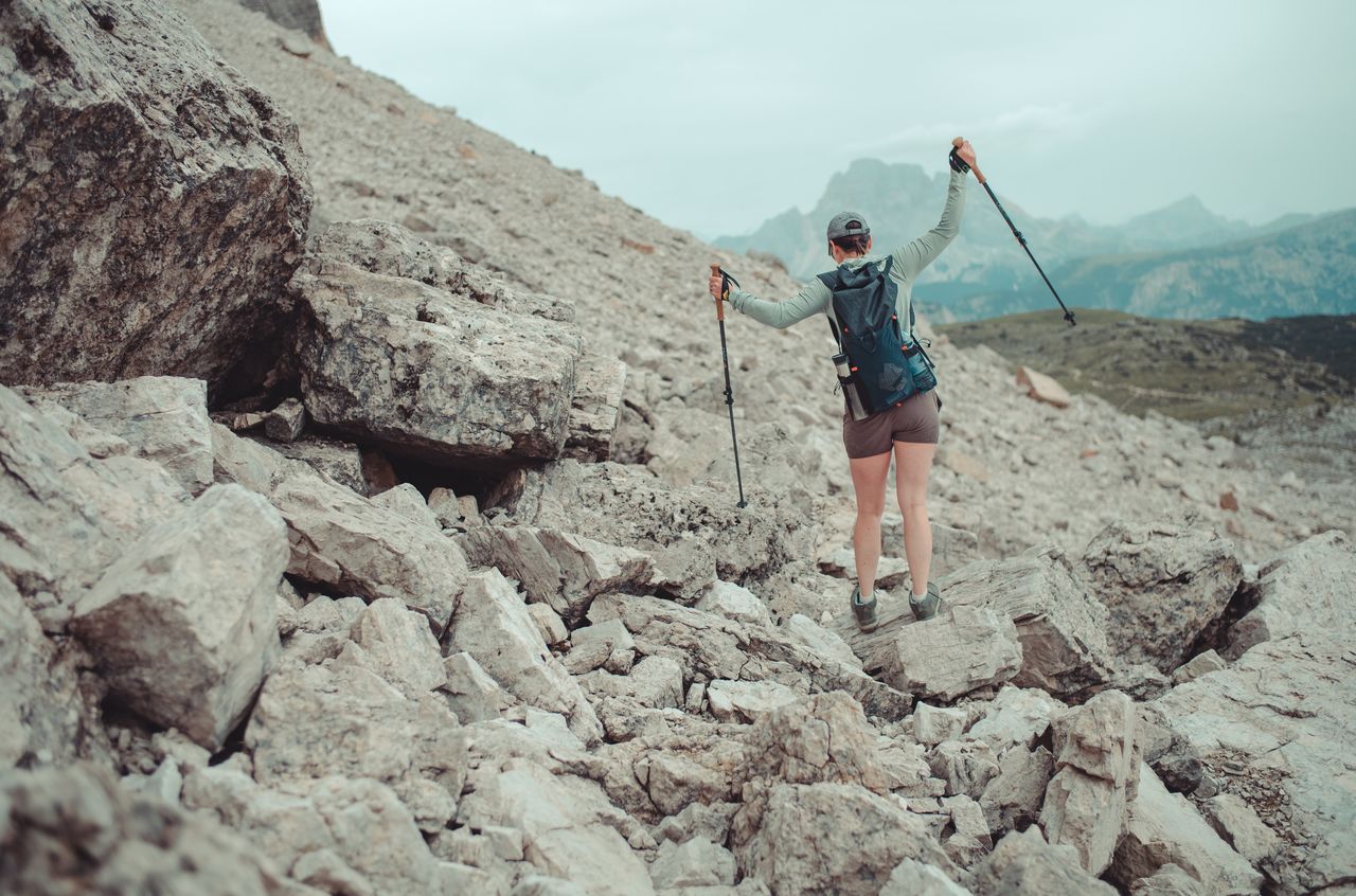 Vanessa standing on a rock, using her trekking poles to maintain her balance.