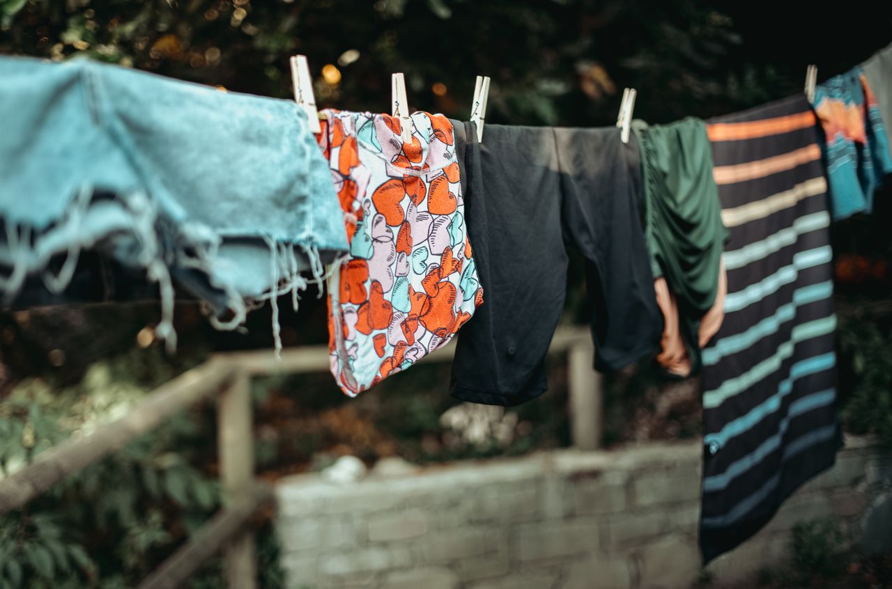 Colorful underwear and clothing hanging on a clothesline outdoors, secured with clothespins.