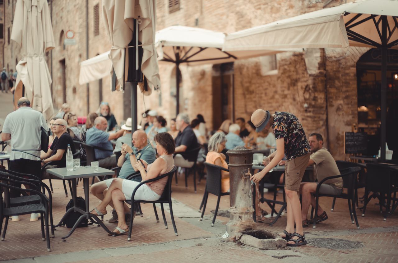 A boy fills his water bottle at a historic fountain in San Gimignano.