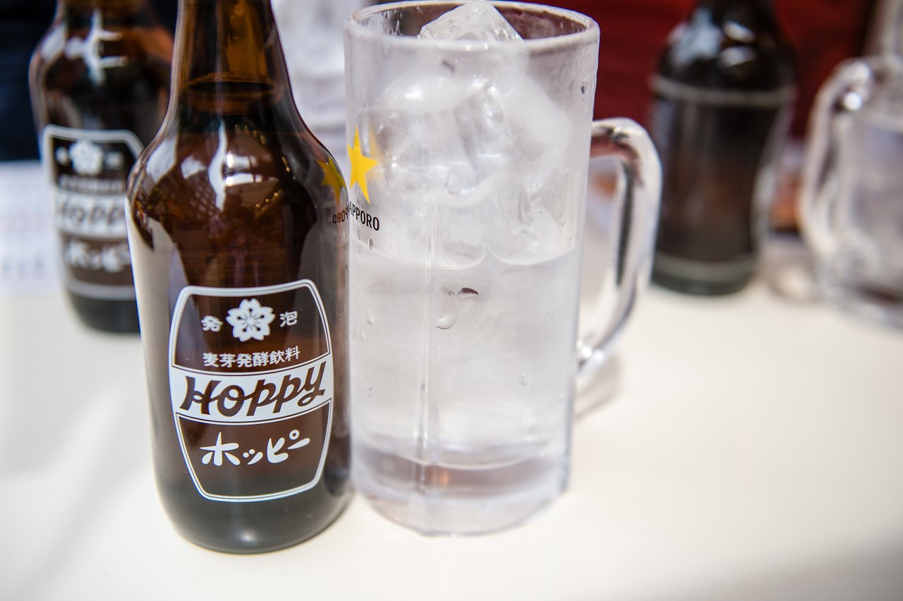 A bottle of Hoppy and a glass of ice water on a table in Japan.
