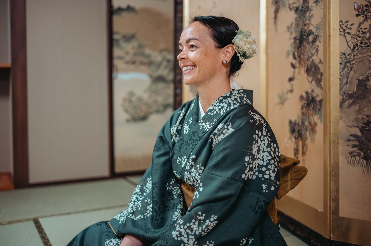 A woman wearing a traditional kimono sits and smiles during a tea ceremony in Tokyo, Japan.