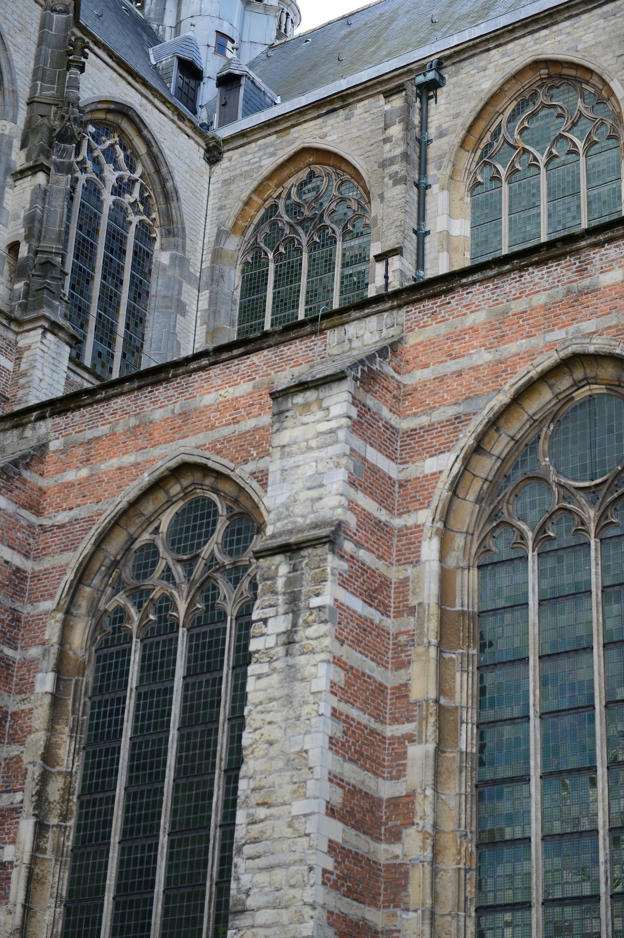 Close-up of a historic church with large arched stained-glass windows and a mix of brick and stone walls.