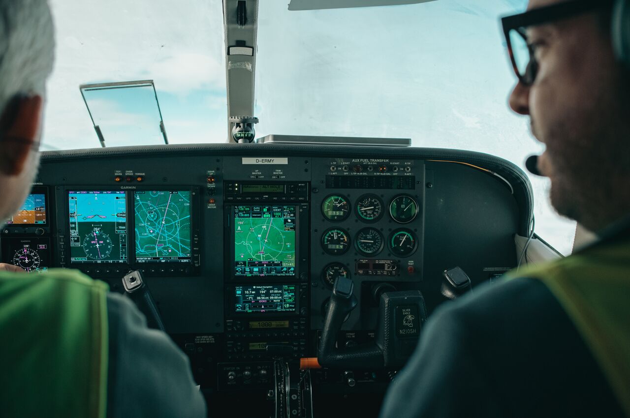 Two people sit in a Cessna cockpit, watching navigation screens and gauges.