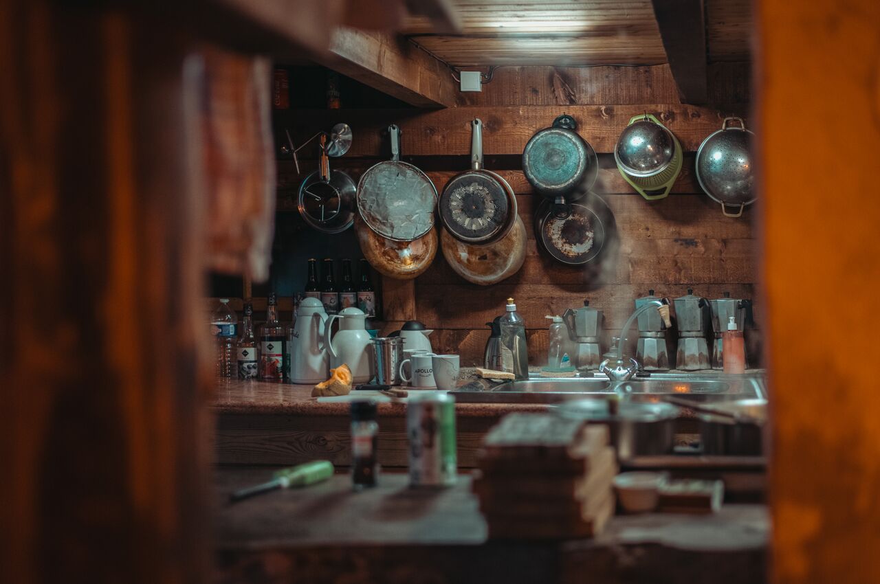 Wooden refuge kitchen with old moka pots and worn pans hanging on the wall.