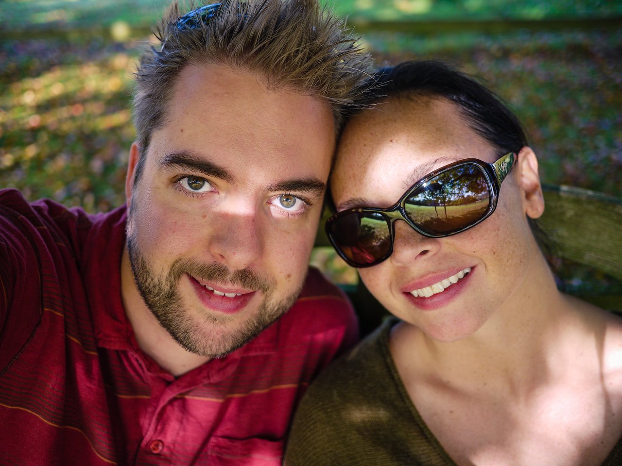 A man and woman sit closely together, smiling at the camera.