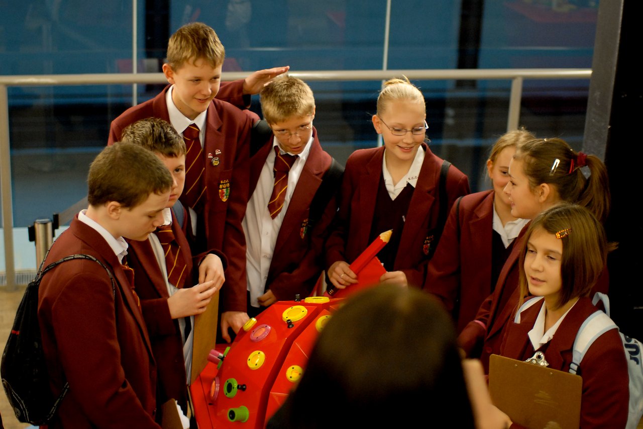 A group of school children in uniforms interact with a colorful exhibit at the Tate Modern museum.