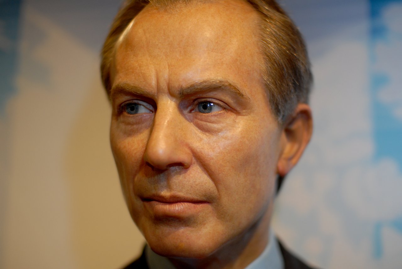 A close-up of a wax figure of a man with short hair, wearing a suit, looking slightly to the side.