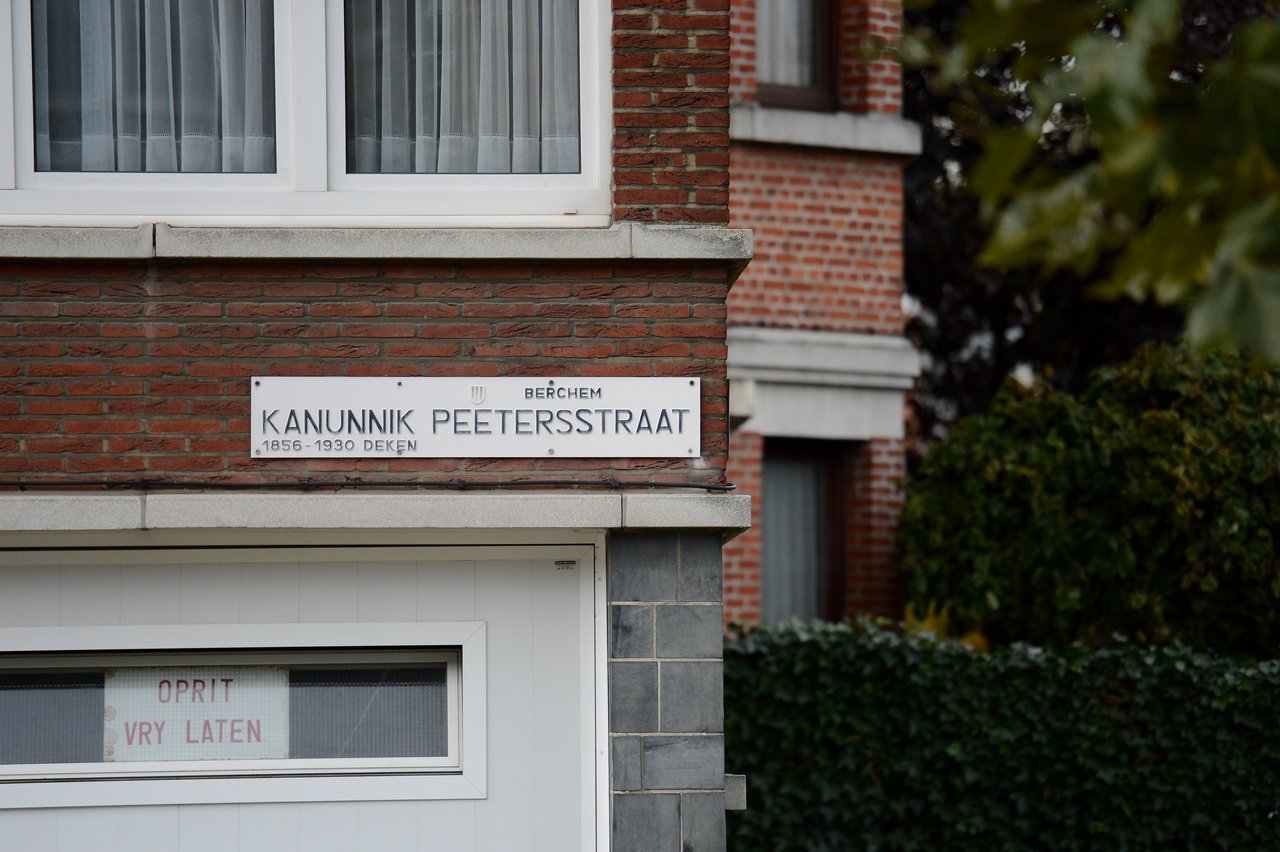 A street sign on a brick building reads "Kanunnik Peetersstraat" with additional text below.