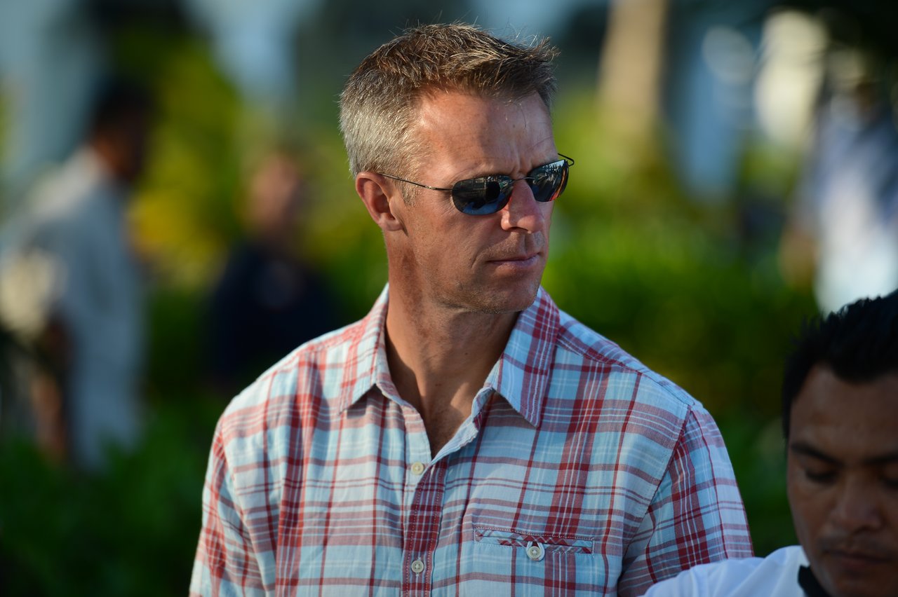 A man in sunglasses and a plaid shirt looks to the side while standing outdoors in Cancun.