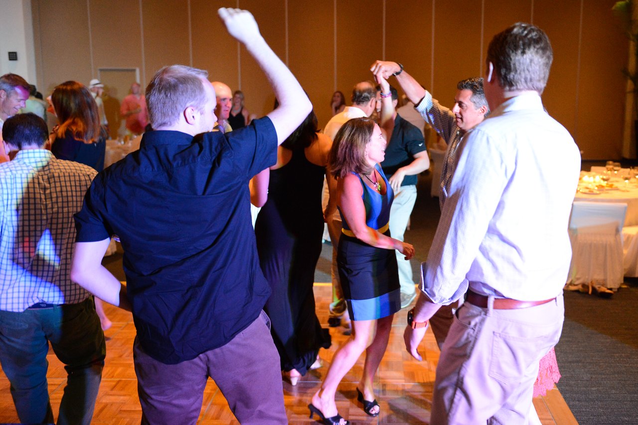 People dancing in a lively indoor setting, with a man twirling a woman on the dance floor.
