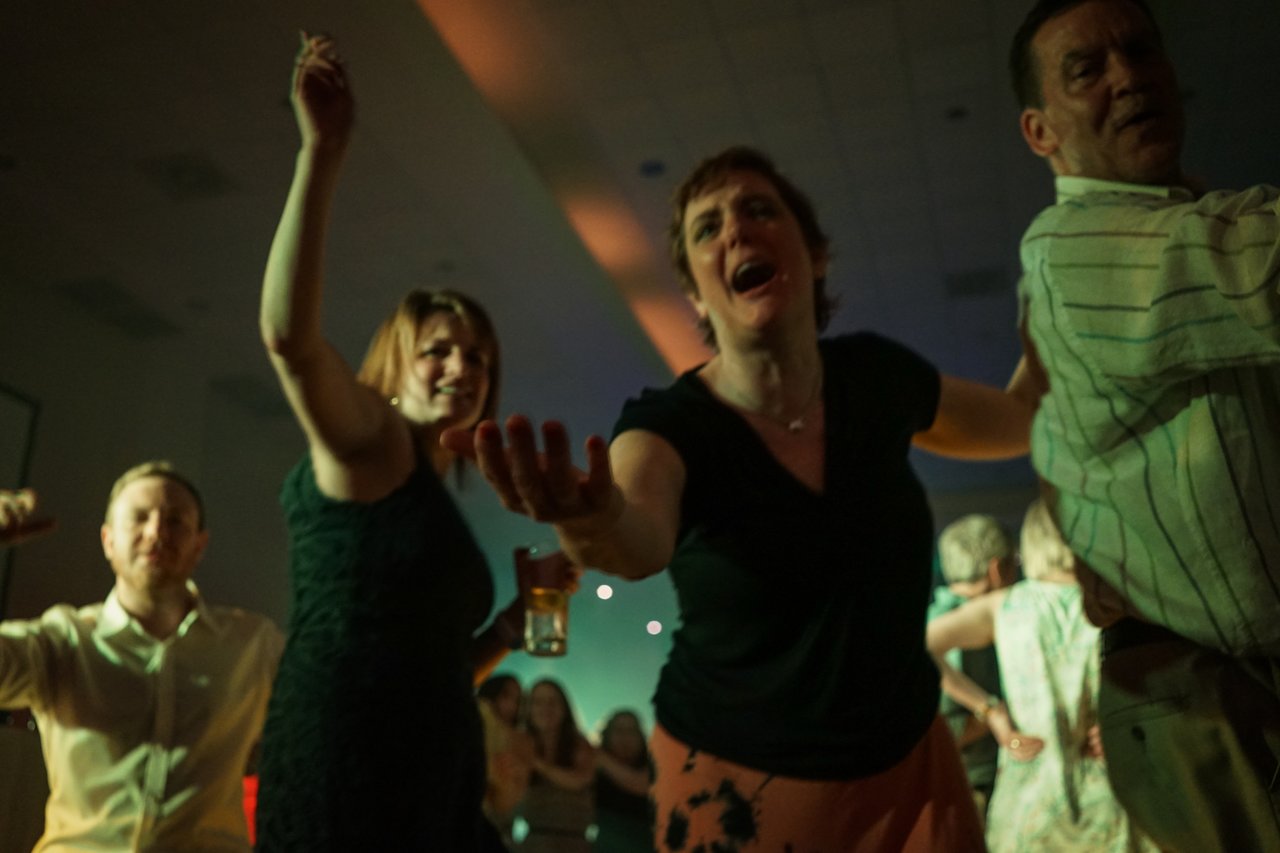 People dancing and celebrating at an award party, reaching out and smiling in a lively atmosphere.