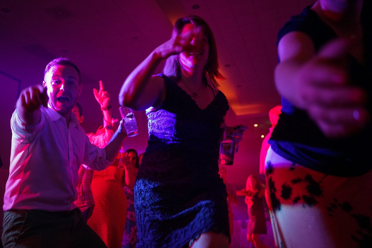 People dancing and celebrating at an award party, with colorful lighting and drinks in hand.