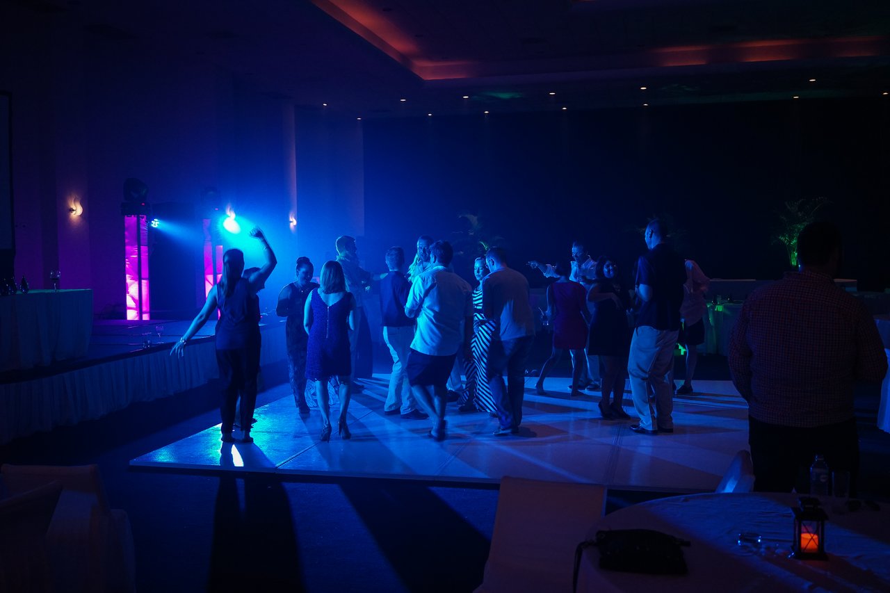 People dancing under colorful lights at an award party, enjoying the celebration in a dimly lit venue.