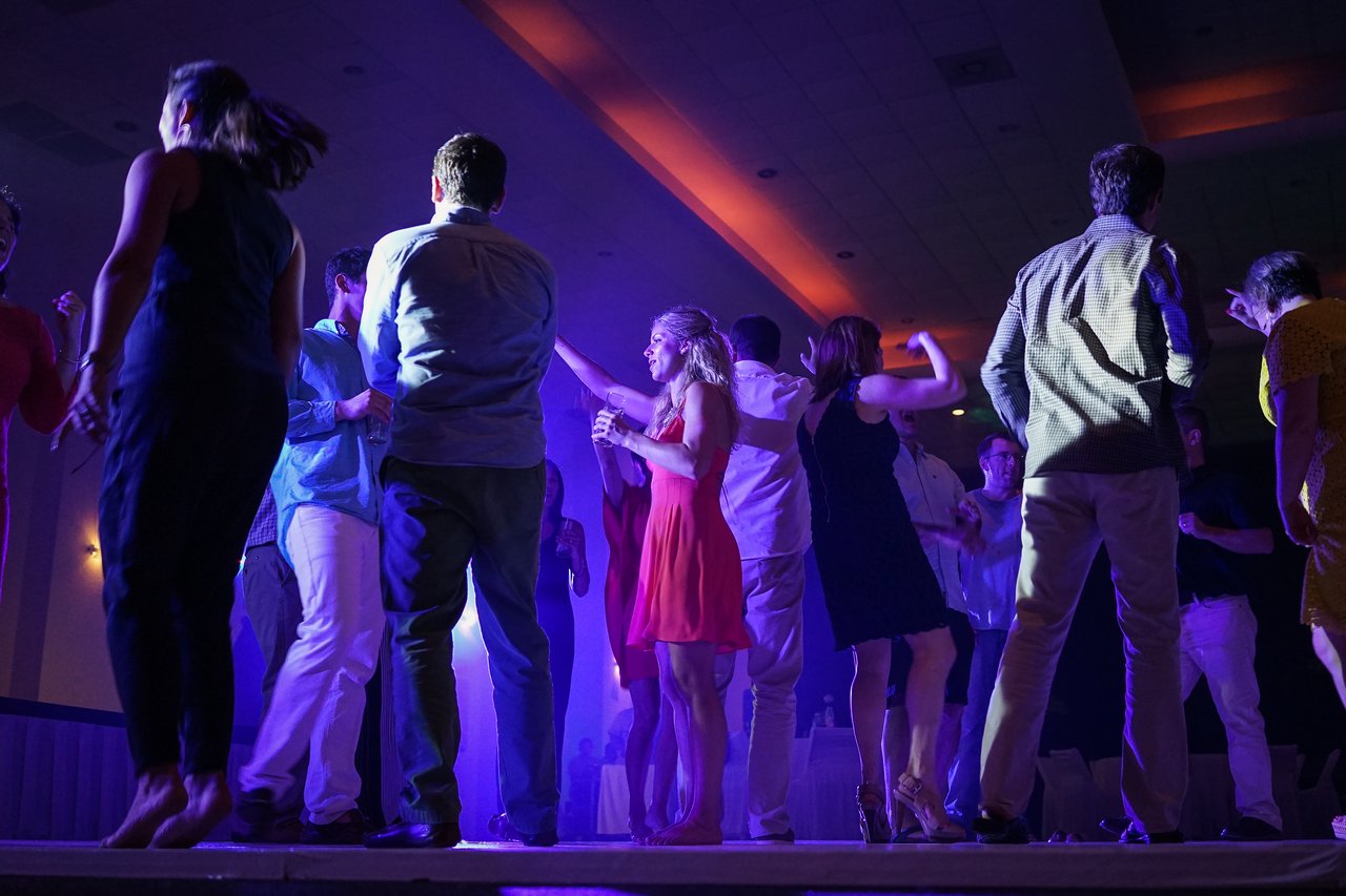 People dancing and celebrating at an award party, illuminated by colorful lights in a lively atmosphere.