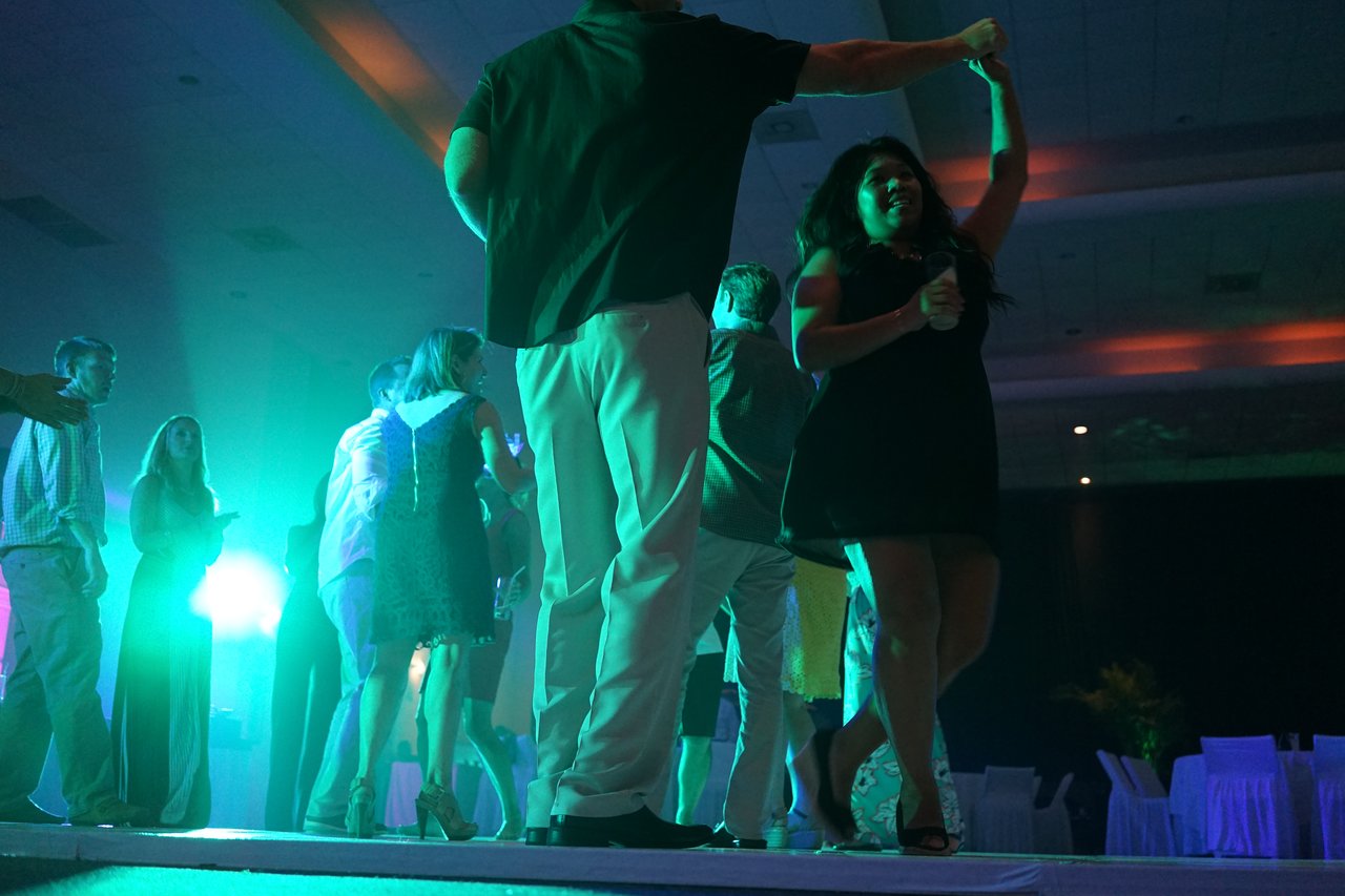People dancing at an award party, with a couple in the foreground holding hands and spinning on the dance floor.