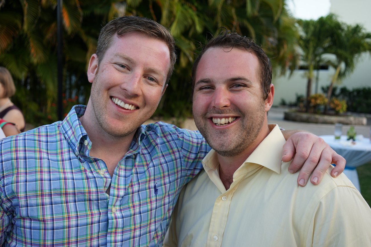 Two men smiling at the camera, one with his arm around the other at an outdoor award party.