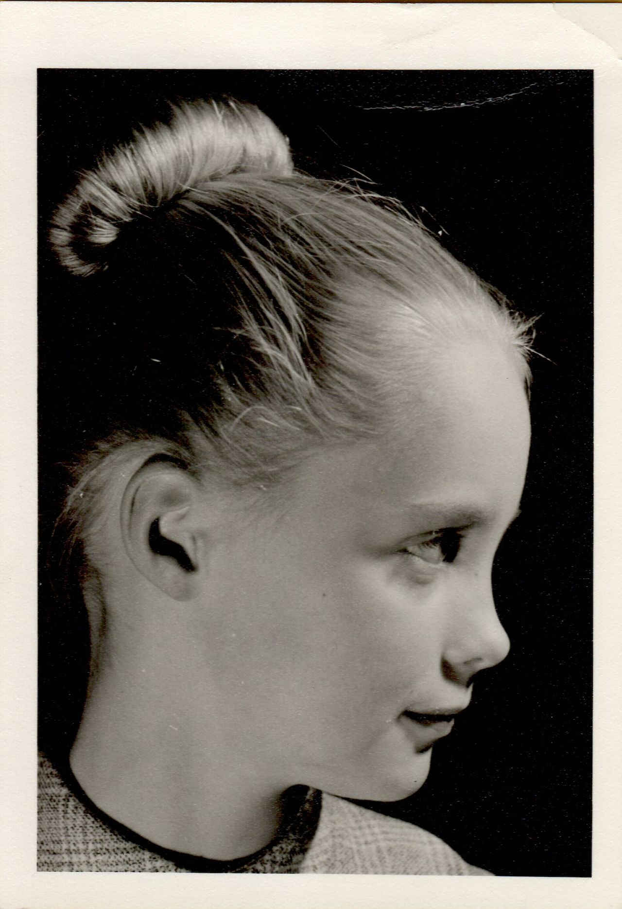 Black-and-white portrait of a young girl in profile, looking to the right with a slight smile.