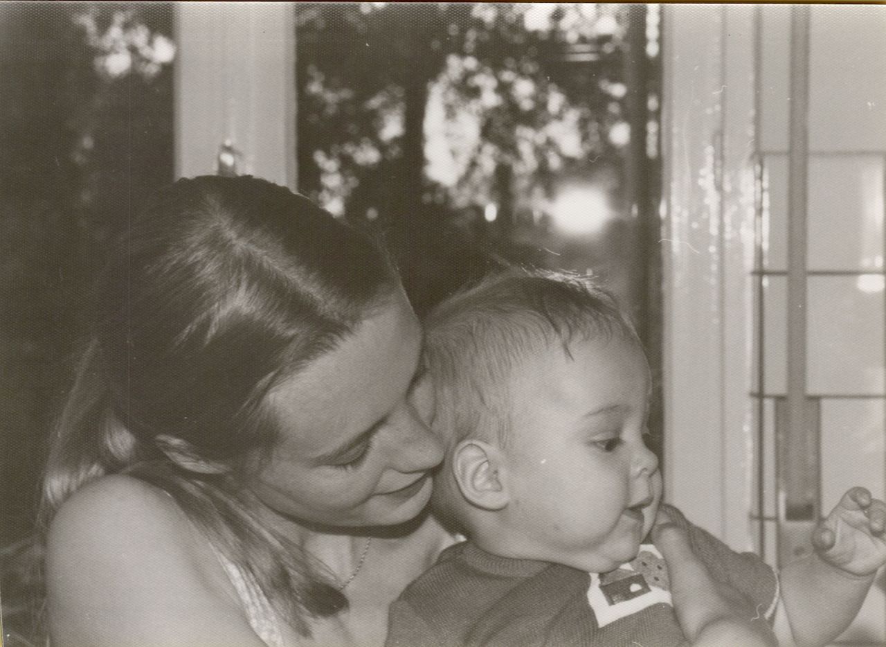 A mother holds her baby close, smiling as she looks at them.