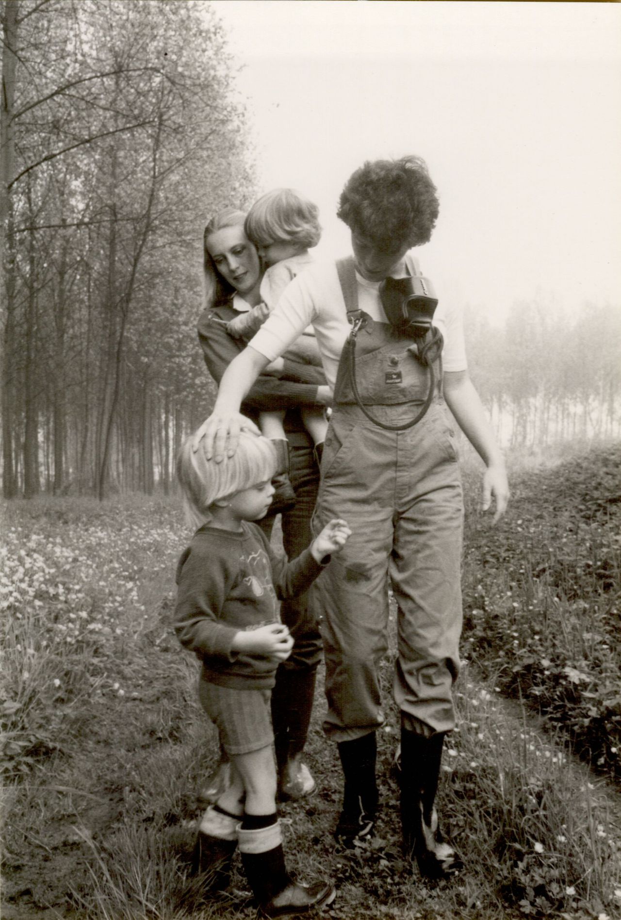 Two adults and two children walk through a grassy field.